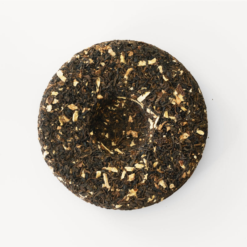 An image of a Rishi Tea & Botanicals Aged Tangerine and Ginger Pu’er on a white surface, perfect for the winter season.