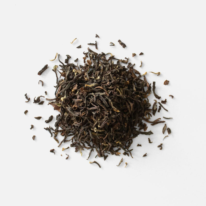 A pile of Darjeeling Second Flush Pussimbing DI71 black tea on a white background by Rishi Tea & Botanicals.