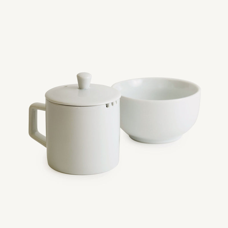 A 3-Piece Porcelain Cupping Set from Rishi Tea & Botanicals, consisting of a white cup and saucer used for professional tea tasting and cupping, placed on a white surface.