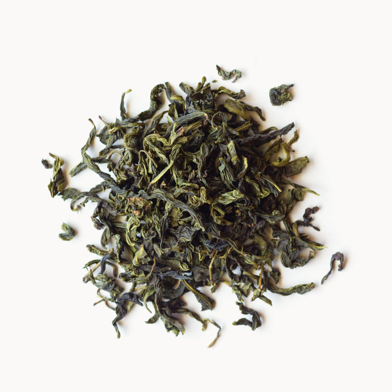 A pile of Bao Zhong green tea on a white background by Rishi Tea & Botanicals.