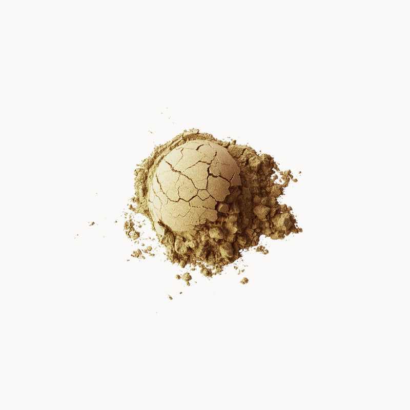 A pile of cracked Rishi Tea & Botanicals' Sweet Houjicha Cocoa Powder compact powder against a white background.