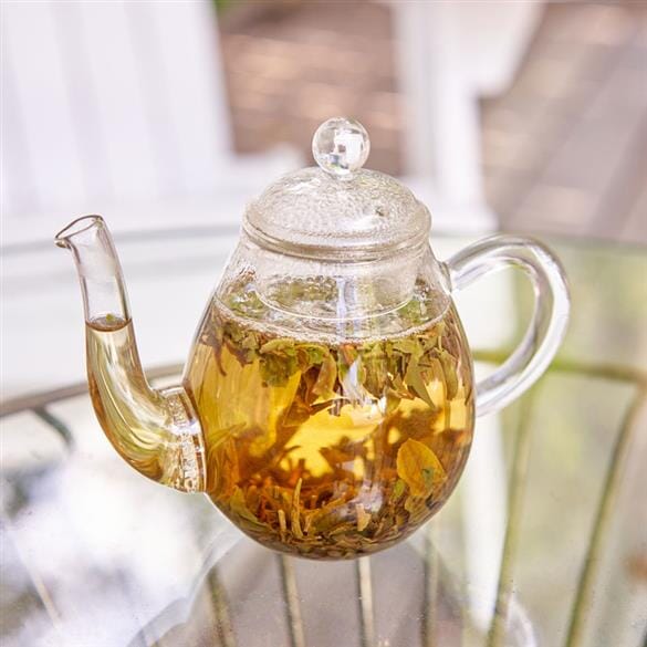 A Classical Pear Shape Teapot filled with Rishi Tea & Botanicals green tea sitting on a table.