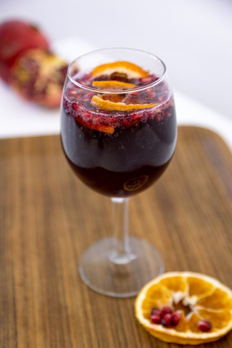 Autumnal sparkling sangria in a wine glass garnished with orange wheels.