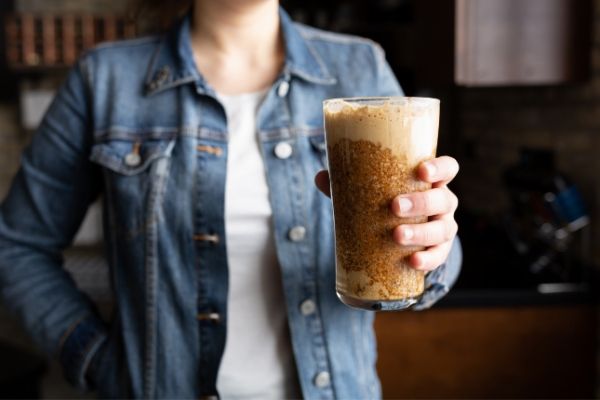 Woman in denim coat holding a pint glass filled with Banoffee Blizzard puree