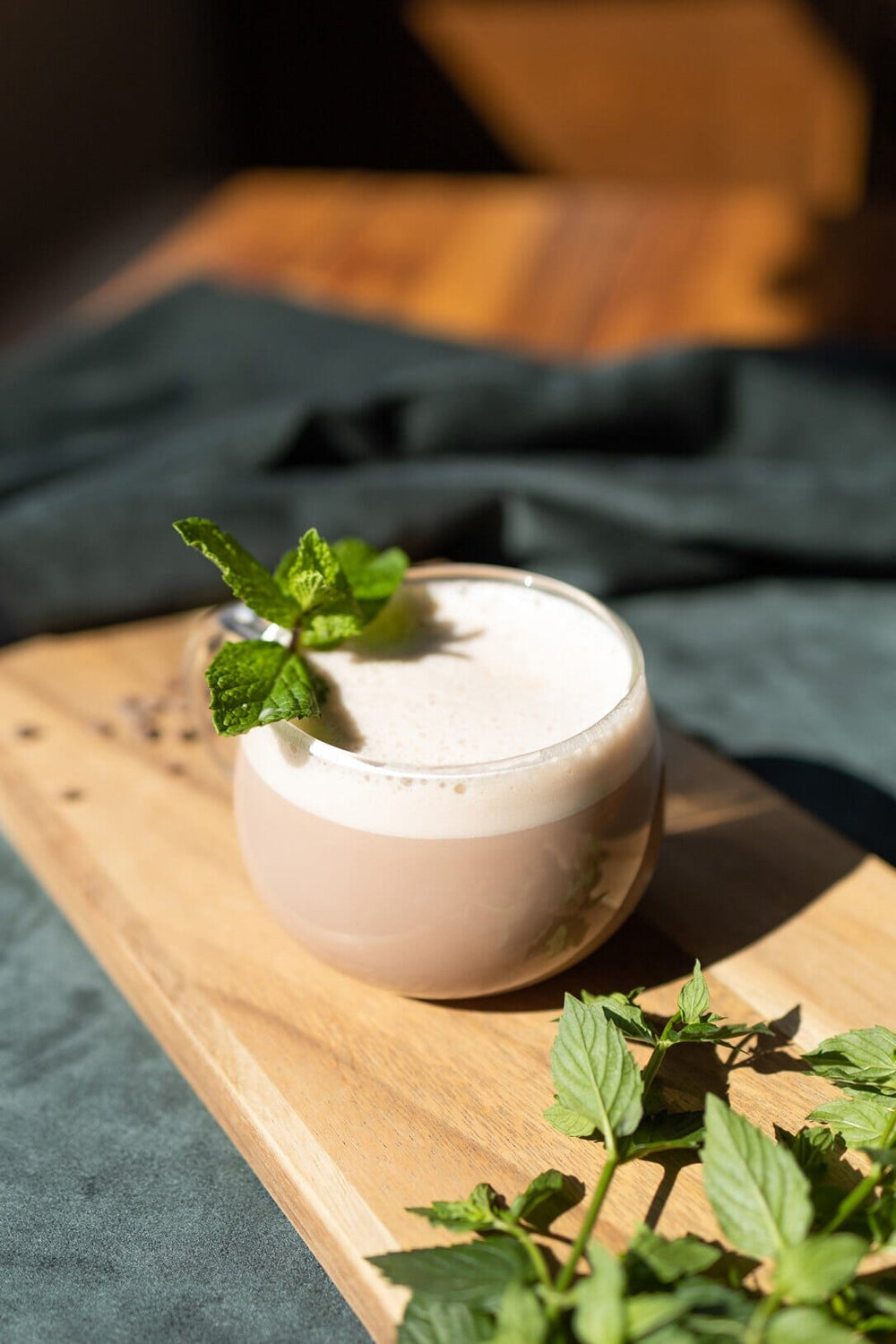 Round glass with frothy hot chocolate and a sprig of mint layered on top