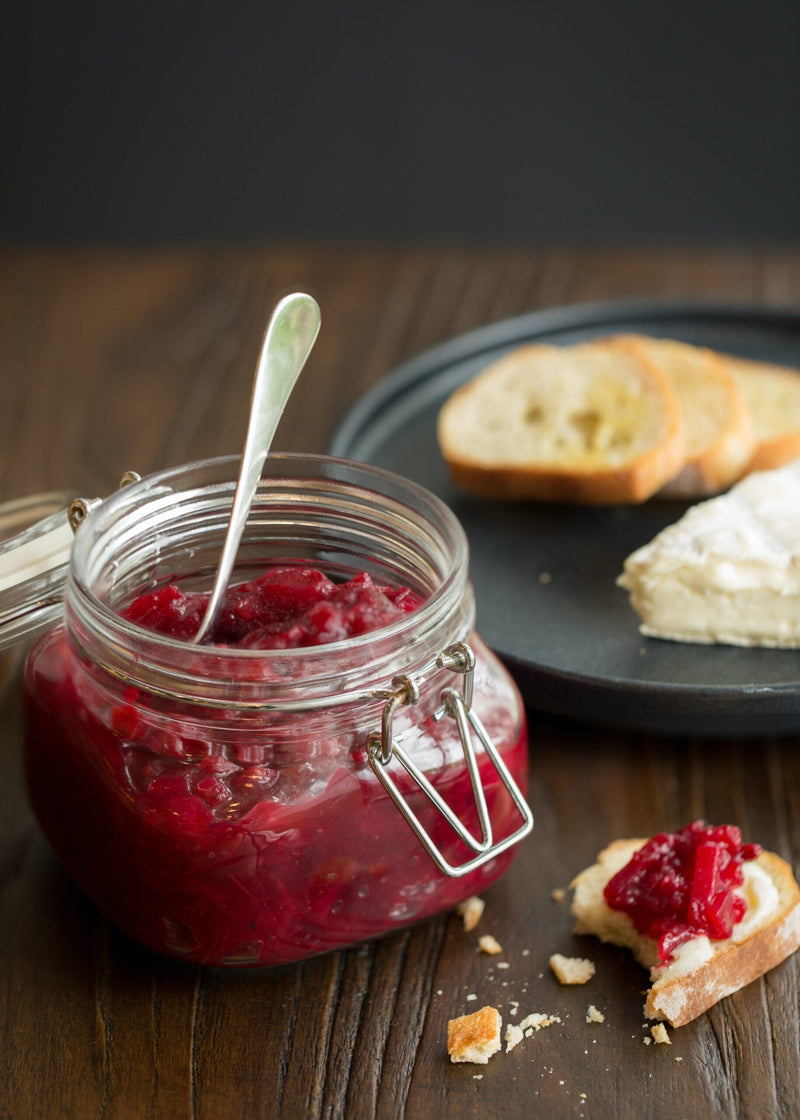 A jar of spiced cranberry pear sauce spread on bread
