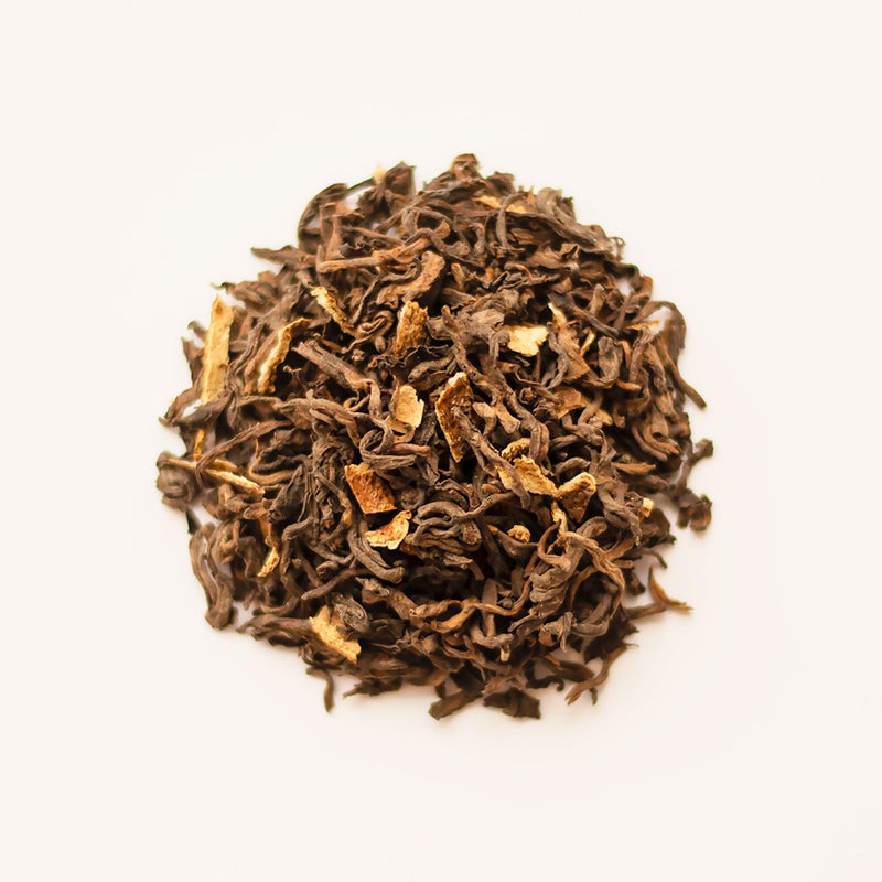 A pile of aged Rishi Tea & Botanicals Aged Tangerine Peel Pu’er tea on a white background.