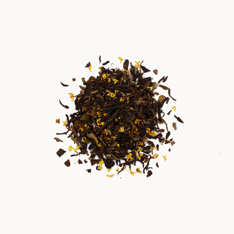 A pile of Osmanthus Black Tea from Rishi Tea & Botanicals, featuring a blend of Yunnan Dian Hong black tea and small yellow Osmanthus flowers, against a white background.