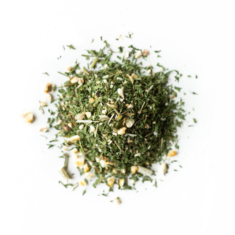 A small pile of Artemisia Qi Tonic from Rishi Tea & Botanicals, featuring a mix of dried herbs and spices with bits of zesty lemon zest, arranged on a plain white background.