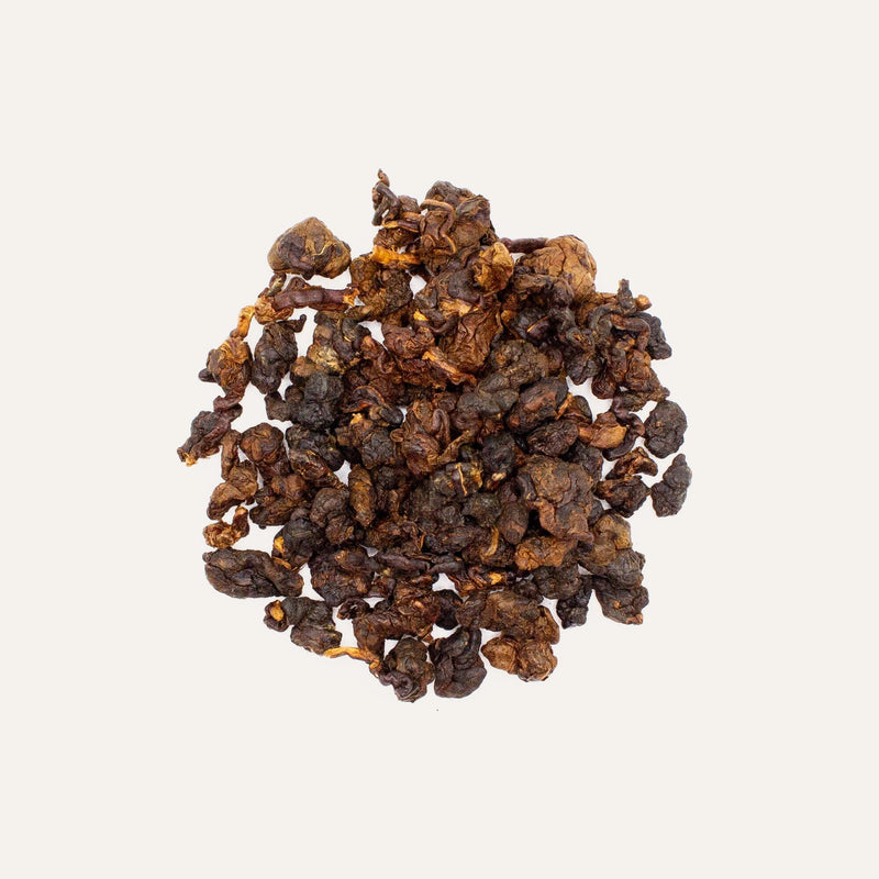 A pile of Japanese Whisky Barrel Aged Chiang Mai tea on a white background, showcasing its rich taste.