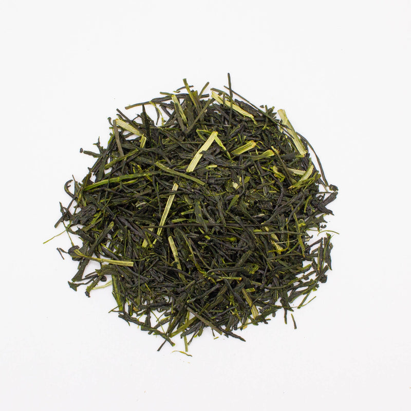 A heap of loose Kawane Shincha leaves from Rishi Tea & Botanicals, known for its light-steamed tea, rests on a plain white background.