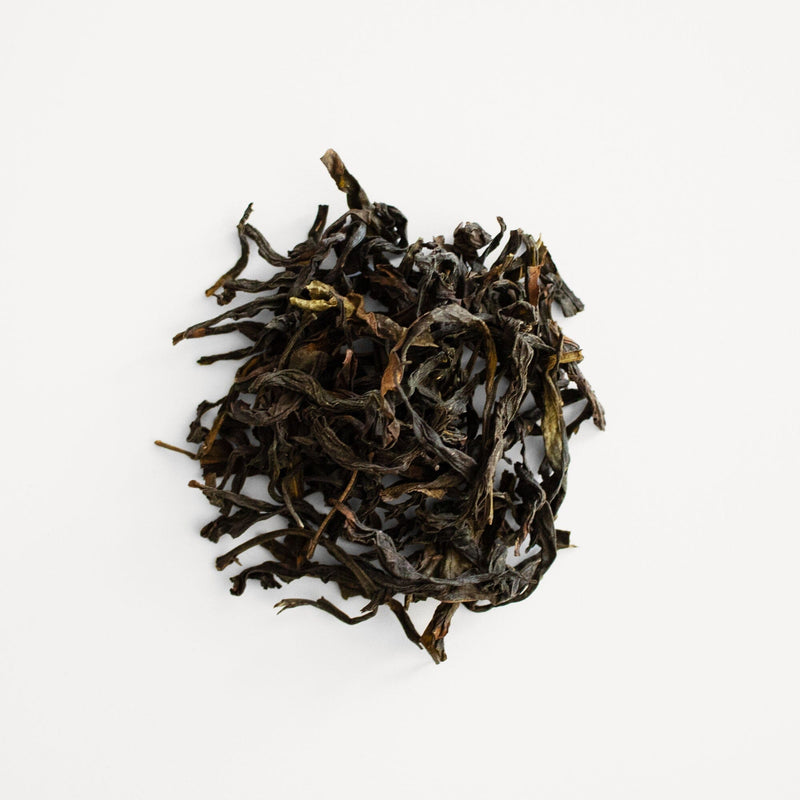 A pile of dried Phoenix Dancong Lan Hua Xiang tea leaves on a white surface by Rishi Tea & Botanicals.