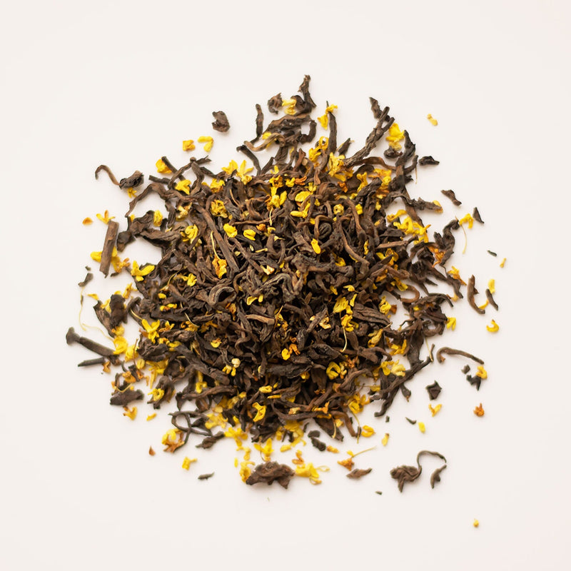 A pile of Osmanthus Pu'er, a fermented tea by Rishi Tea & Botanicals, adorned with vibrant yellow flowers that exudes a comforting and warming effect.