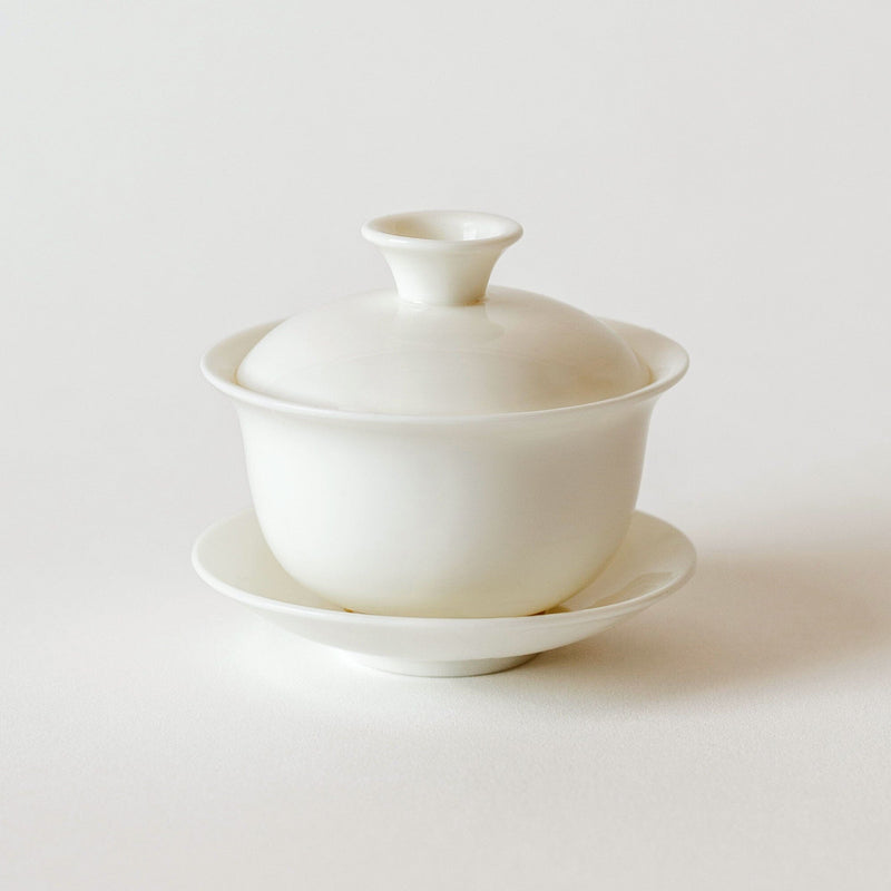 A white Gaiwan Teapot and saucer on a white surface, showcasing premium oolong tea from Rishi Tea & Botanicals in a stylish gaiwan.