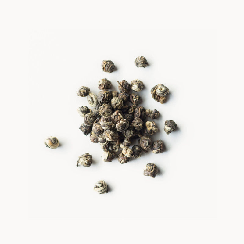 A pile of Jasmine Pearls black tea on a white background from Rishi Tea & Botanicals.