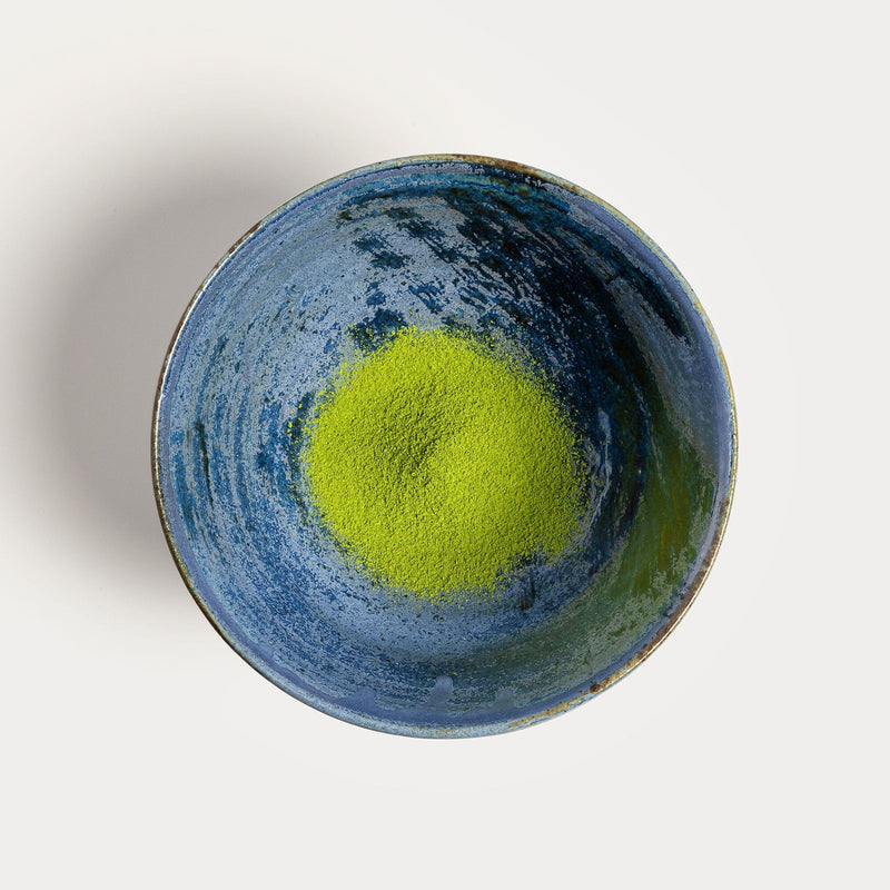 Matcha Sakimidori by Rishi Tea & Botanicals in a blue bowl on a white surface.