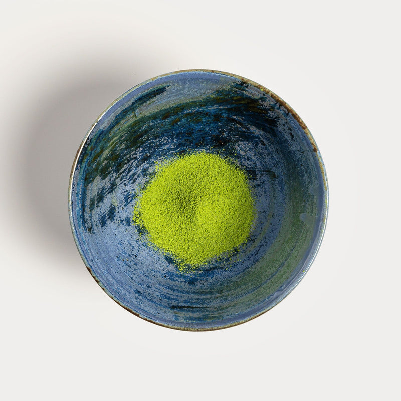 A bowl of green Matcha Tsuyuhikari powder on a white background by Rishi Tea & Botanicals.