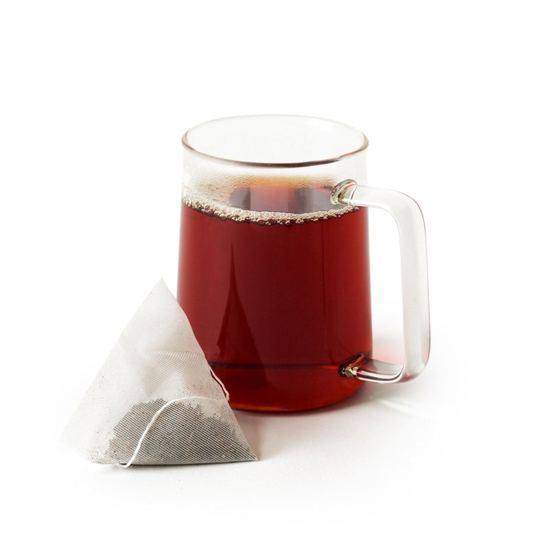 A cup of Ruby Oolong Double-Dose tea with a Rishi Tea & Botanicals tea bag next to it.