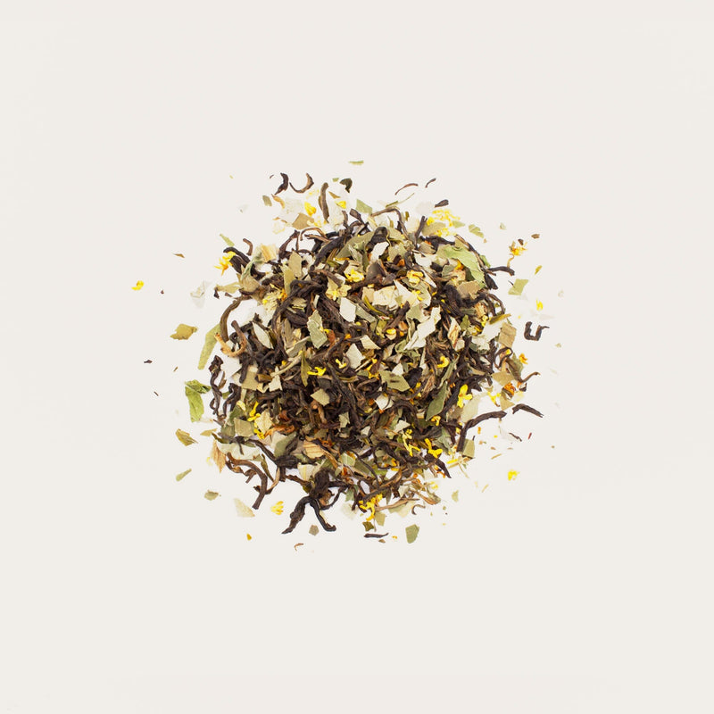 A scattered mix of Lotus Leaf Black Tea by Rishi Tea & Botanicals, featuring elegant dark black tea leaves, light spearmint, and yellow leaves, is beautifully displayed on a white background.