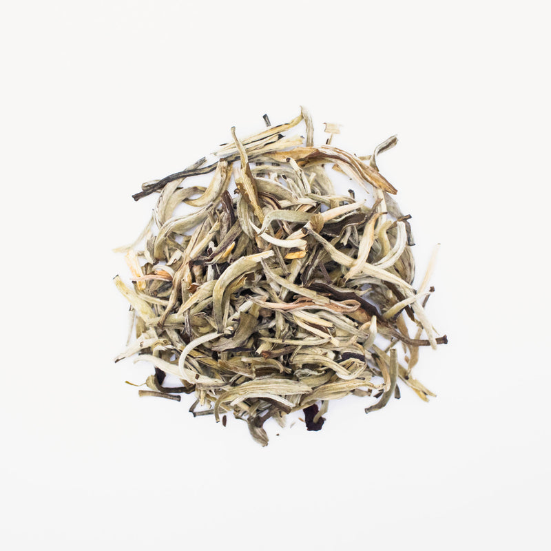 A small pile of loose leaf Jasmine Silver Needles from Rishi Tea & Botanicals rests on a white background, inviting tea connoisseurs to indulge in its delicate elegance.