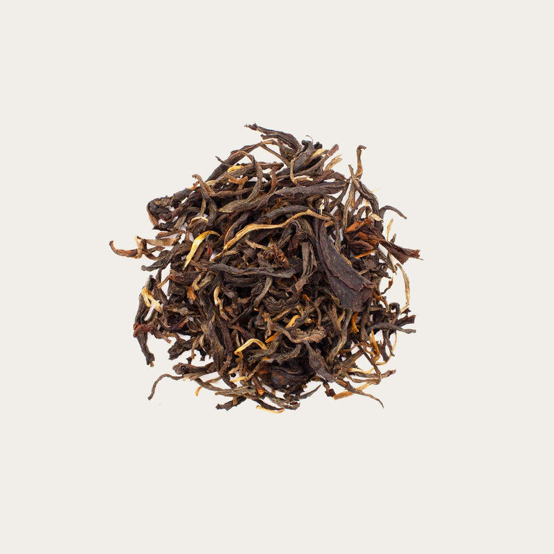 A pile of loose leaf Sun-Dried Dian Hong Mao Feng Black Tea from Rishi Tea & Botanicals rests on a plain white background.