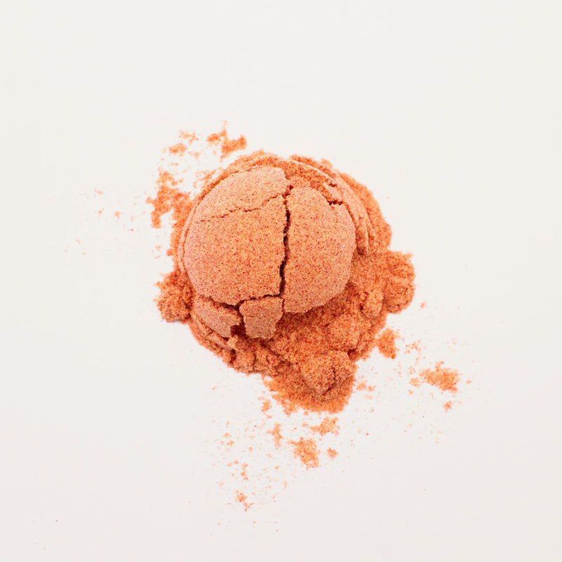 A mound of the reddish-brown Passionfruit Hibiscus Powder from Rishi Tea & Botanicals on a white surface, featuring a slightly cracked spherical shape in the center.