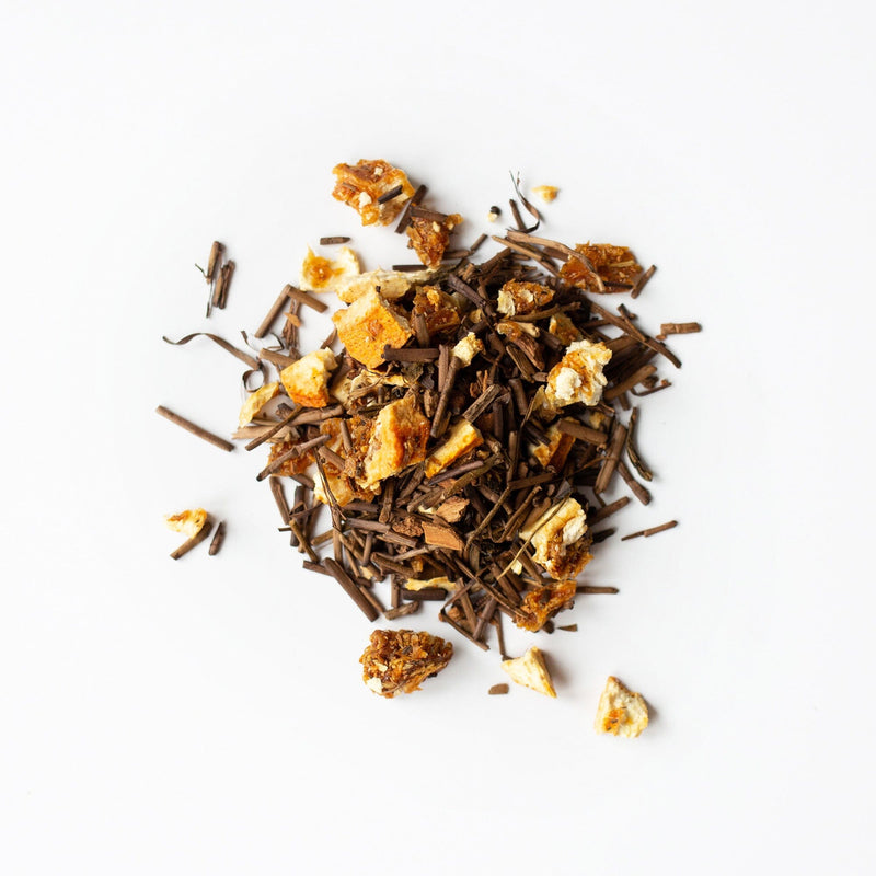 A pile of loose-leaf Houjicha Cinnamon Orange tea by Rishi Tea & Botanicals, featuring citrusy orange peel, rests on a white background.