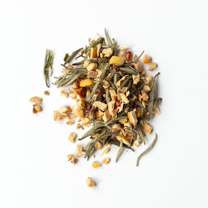 A delicate pile of Quince Ginger blend by Rishi Tea & Botanicals, featuring Silver Needles white tea with green leaves, dried orange pieces, and small red seeds, rests on a white background.