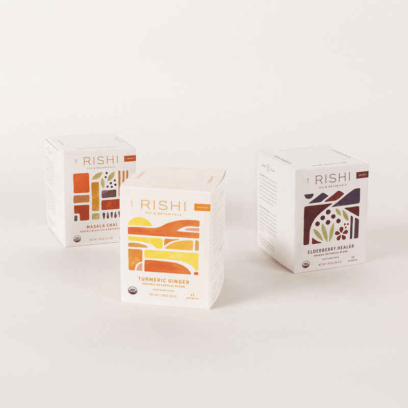 Displayed against a white background are three boxes from the Rishi Tea & Botanicals' Winter Sachet Collection, featuring a premium seasonal trio: Masala Chai, Turmeric Ginger, and Elderberry Healer.