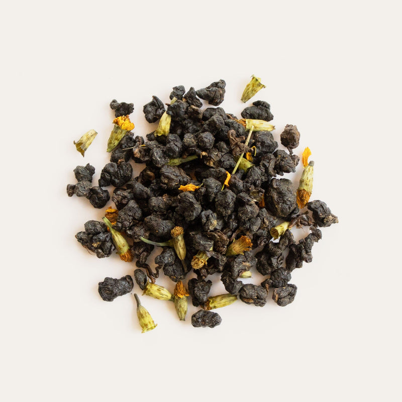 A pile of black tea on a white surface showcasing the stunning flavors of Sweet Starflower Oolong by Rishi Tea & Botanicals.