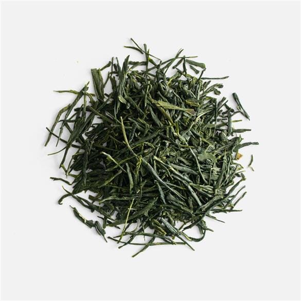 A pile of Hon Yama Okawa Shincha green tea leaves on a white background from Rishi Tea & Botanicals.