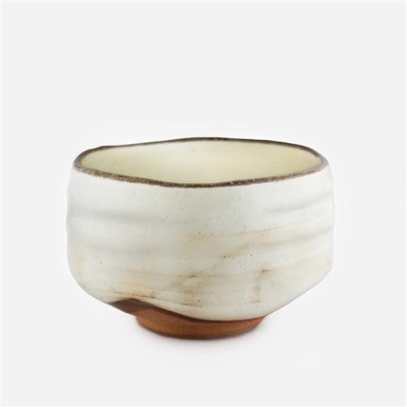 A small Wabi Sabi Raku Matcha Bowl on a white surface from Rishi Tea & Botanicals.