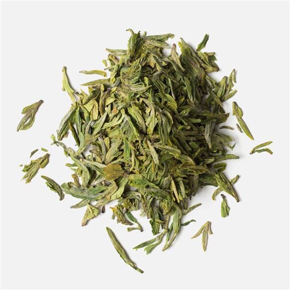 A pile of Dragon Well Long Jing 43 tea leaves on a white background by Rishi Tea & Botanicals.