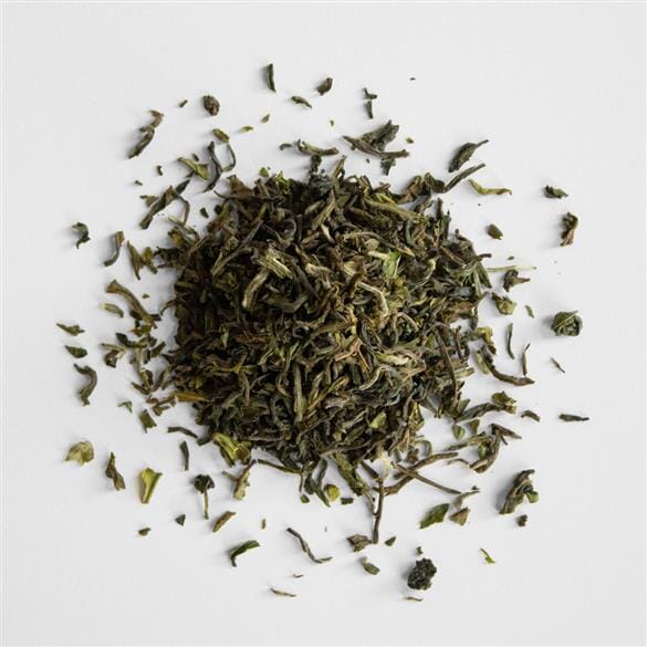 A pile of Darjeeling First Flush Lingia EX1 green tea on a white surface from Rishi Tea & Botanicals.