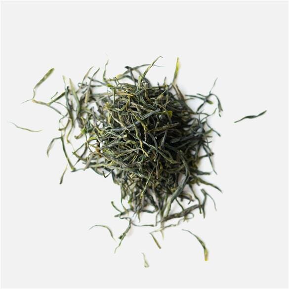 A pile of Yulu Jade Dew green tea leaves on a white background by Rishi Tea & Botanicals.