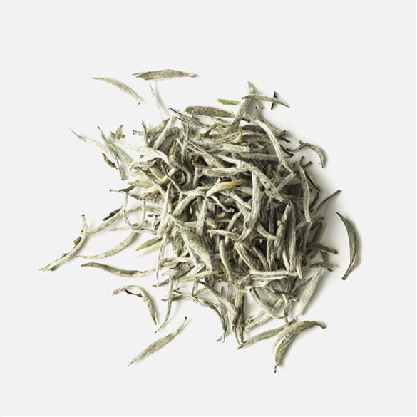 A pile of Fuding Silver Needles tea leaves on a white background, by Rishi Tea & Botanicals.