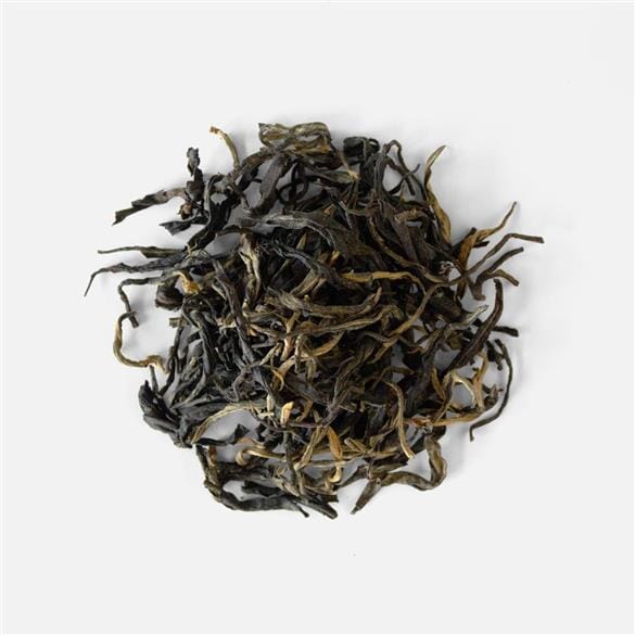 A pile of Sun Dried Red Tea Pu Muen leaves on a white background from Rishi Tea & Botanicals.