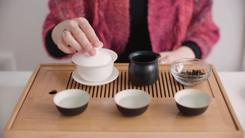 Person with teapot, cups and tea on a table