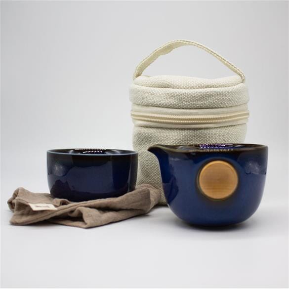 A Brewing Nest Ceramic Travel Teapot tea set with a Rishi Tea & Botanicals bag next to it.
